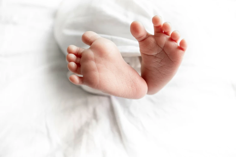 the feet of a baby that is laying on top of a white blanket