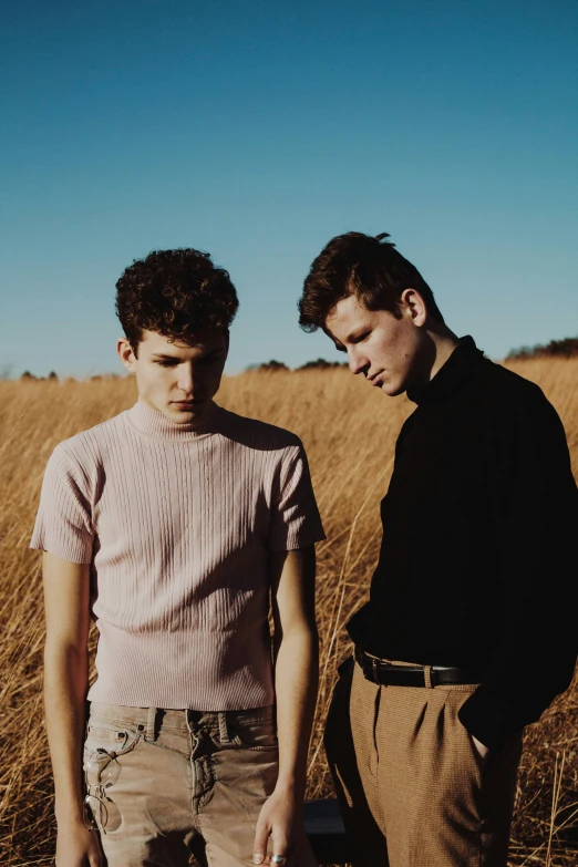 two men in a field, one is looking at soing