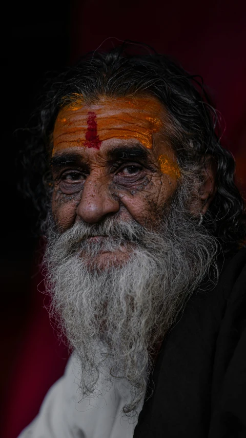 an old man with long beard wearing orange painted on his face