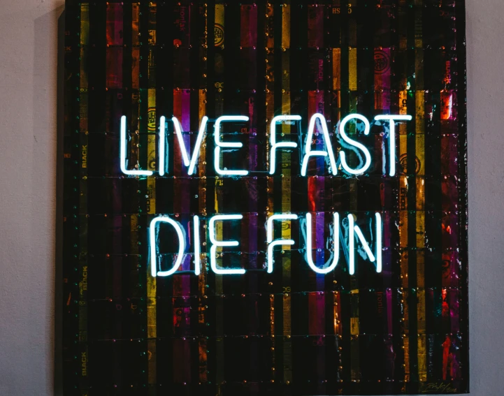 an illuminated sign that reads live fast die fun on the wall