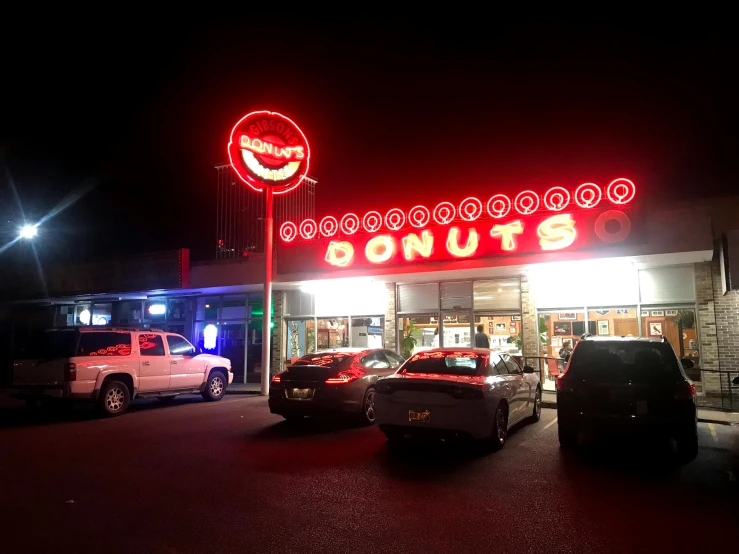 two trucks parked in front of a donut shop