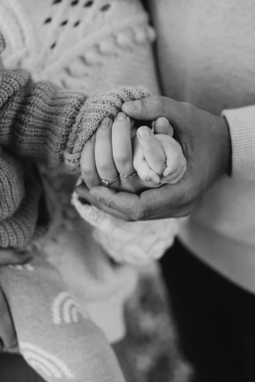 the mother holds her newborn son's hands