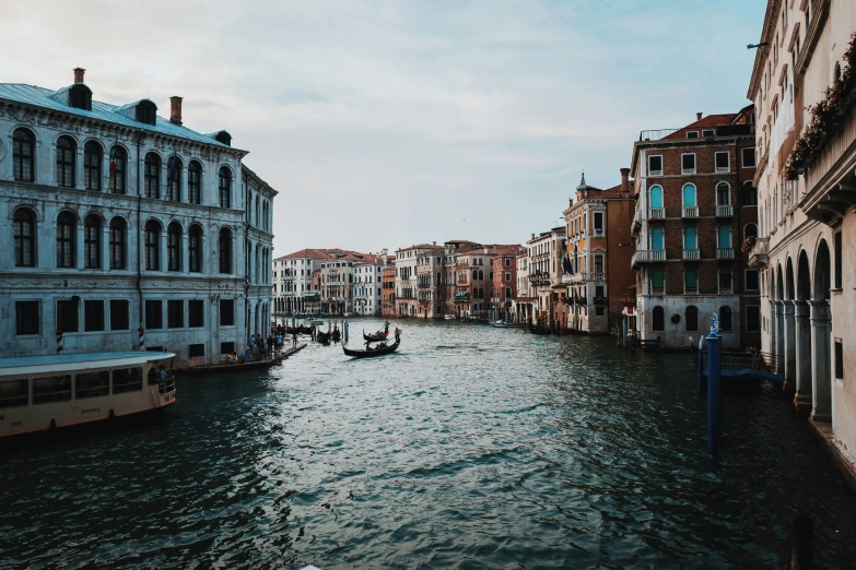 a couple of people ride a boat down the water in a canal