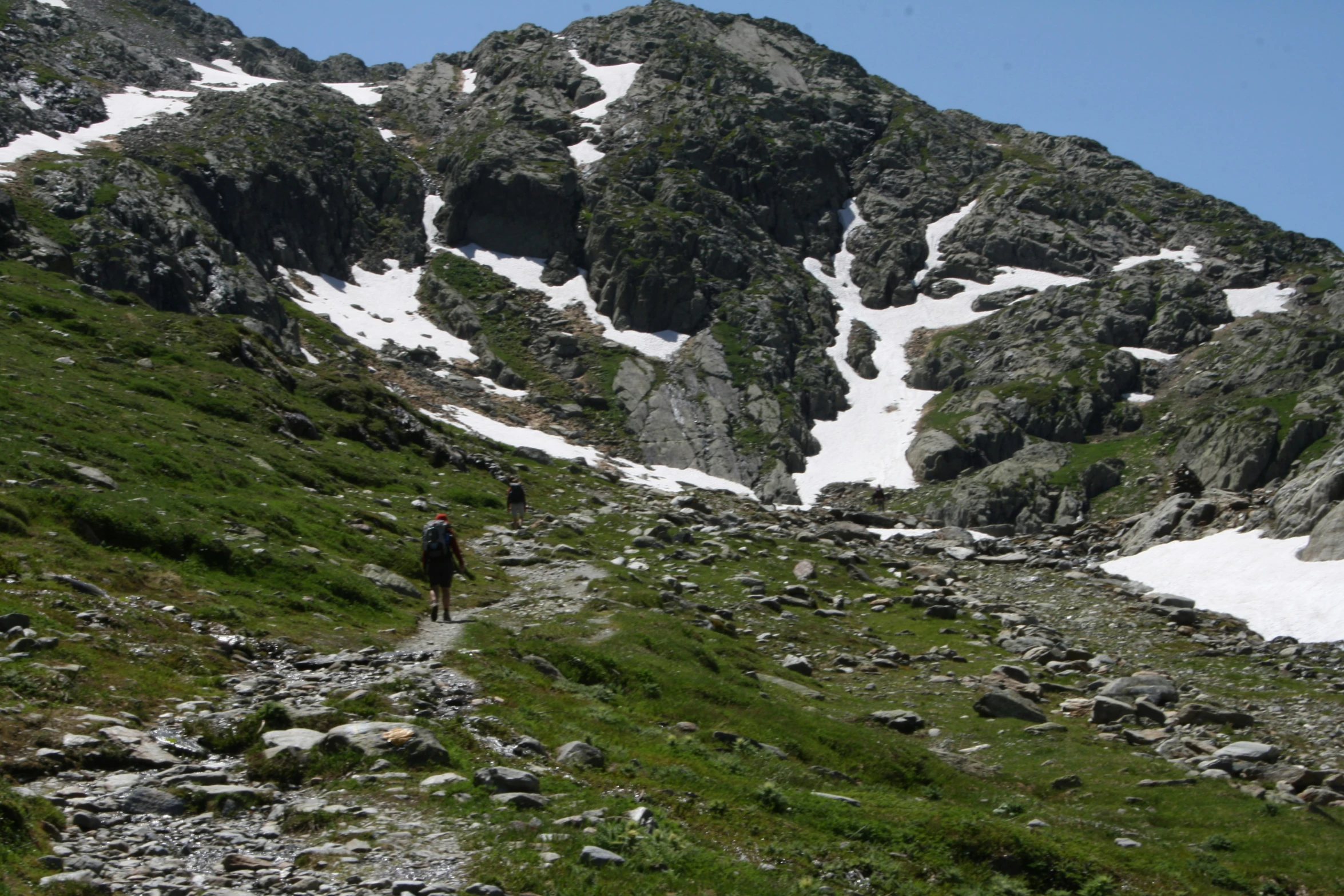 a couple of people hiking down a rocky mountain