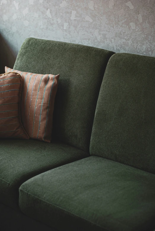 there is an green sofa with two pillows