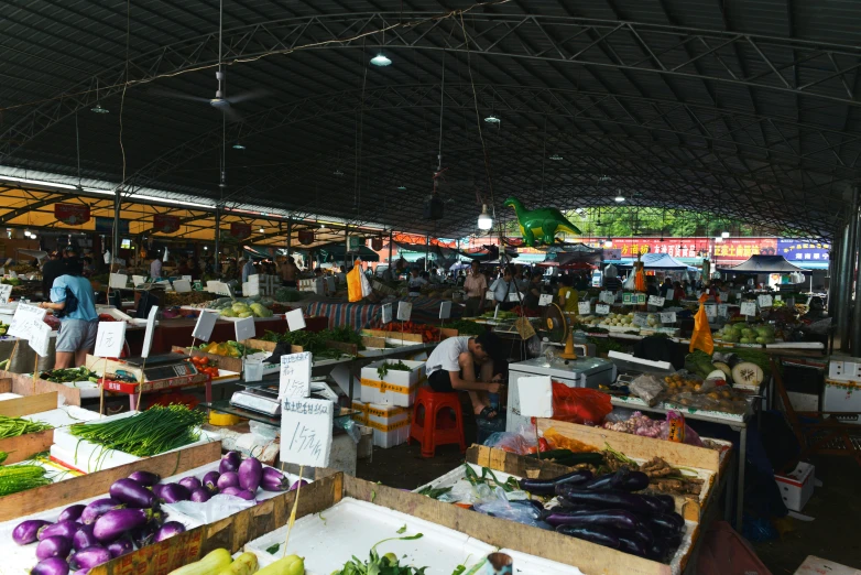 people shopping at an indoor market with fruits and vegetables