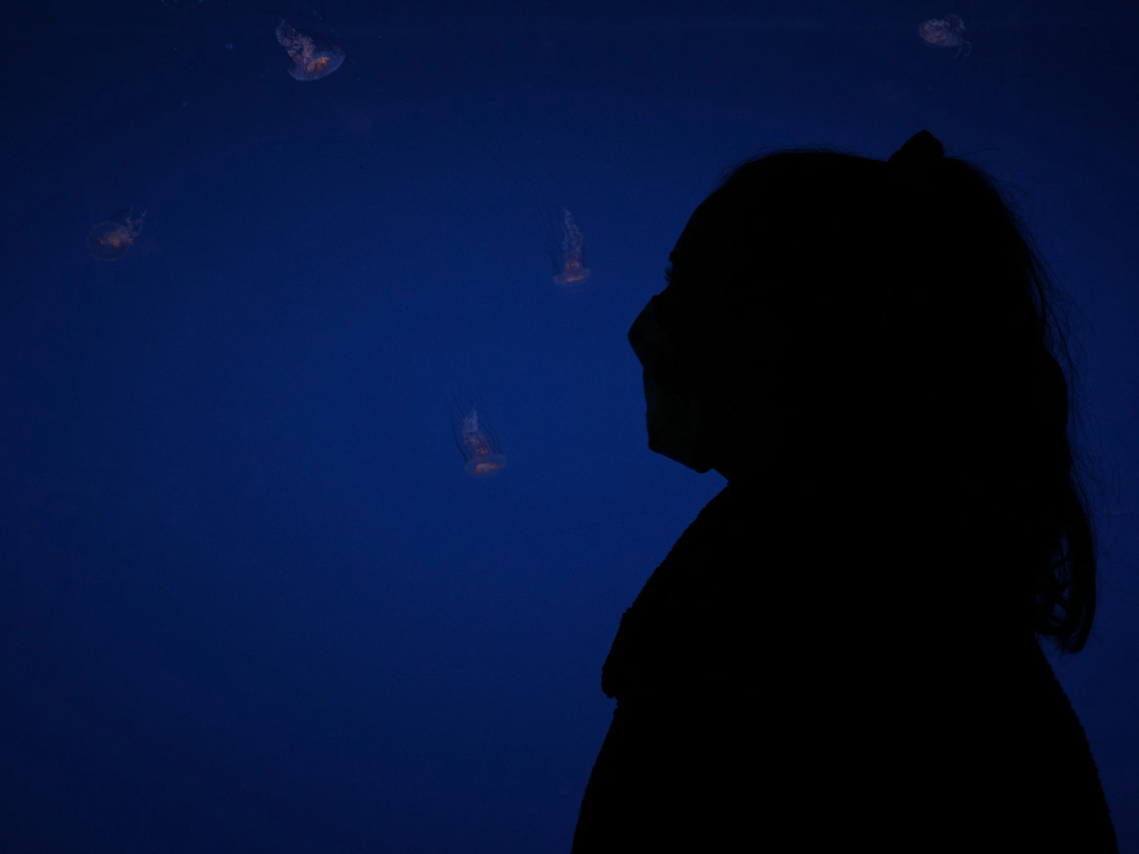 a woman standing in the dark looking to her right