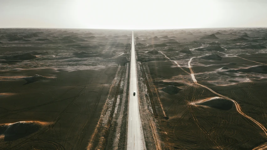 a lone road crosses across an expanse of dry grass