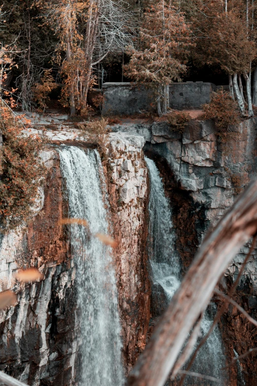 a tall waterfall with trees around it in the woods