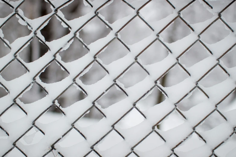 close up of a metal mesh fence, with only the snow still falling