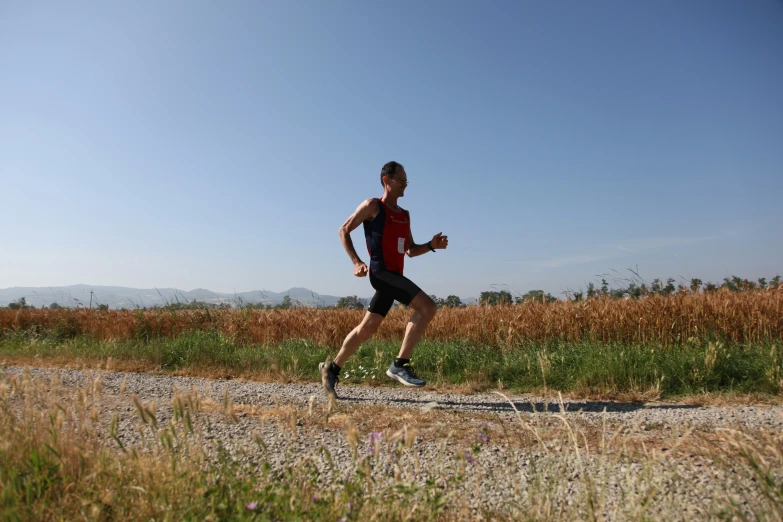 a man running on a road near some tall grass