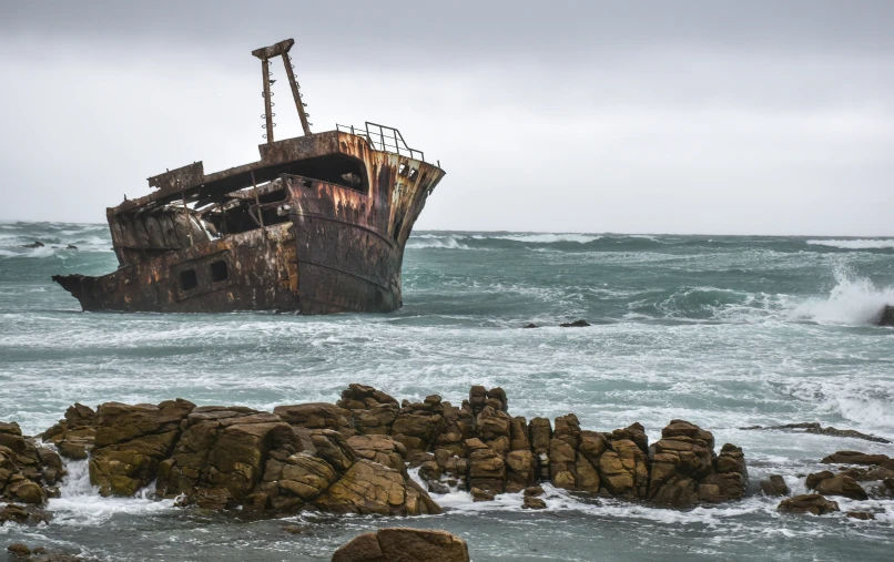 an old rusted ship sitting on top of some rocks