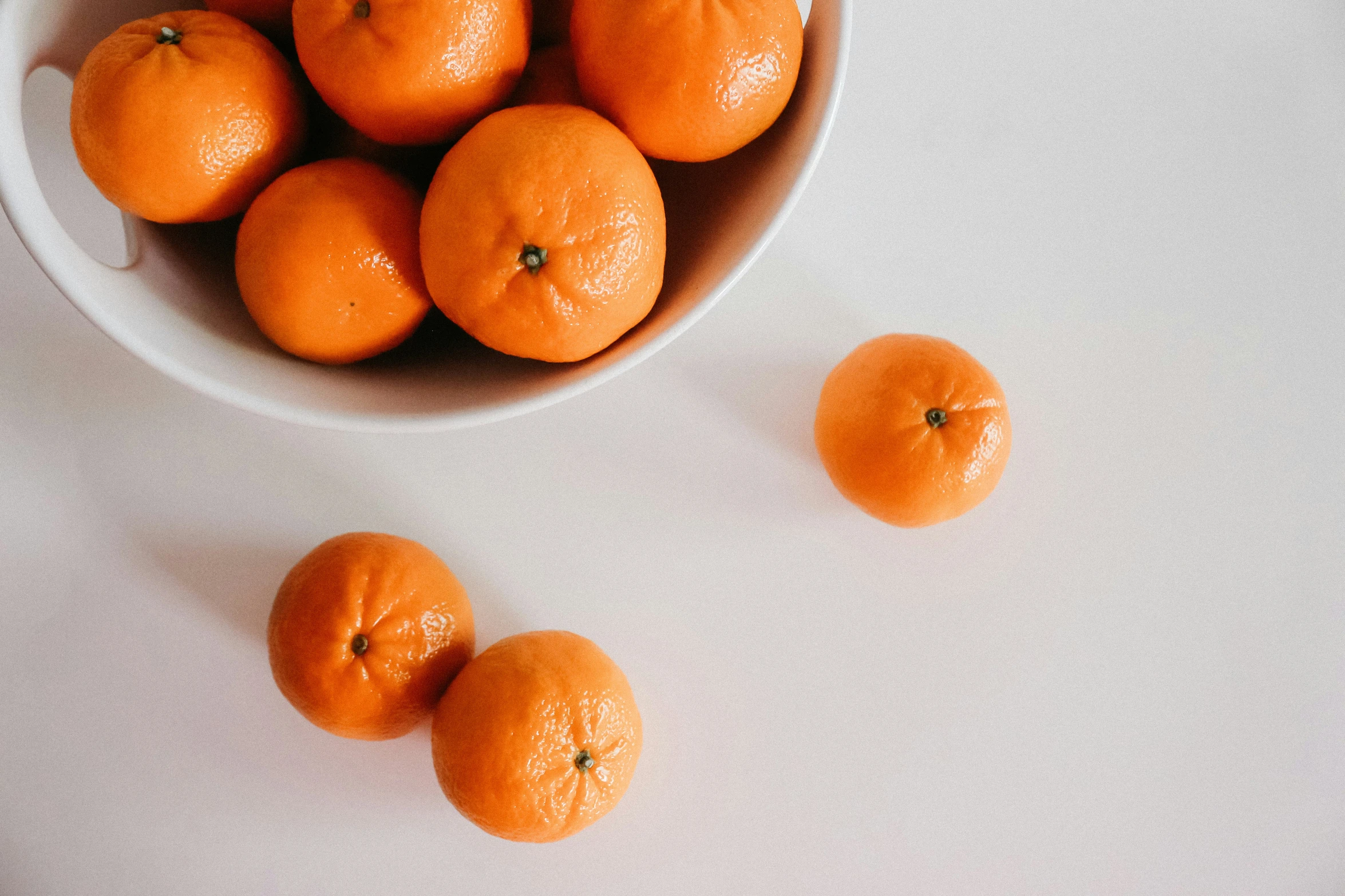 a bowl filled with oranges on top of a white counter