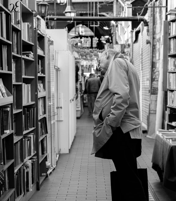 a black and white po of a man walking in an old book store