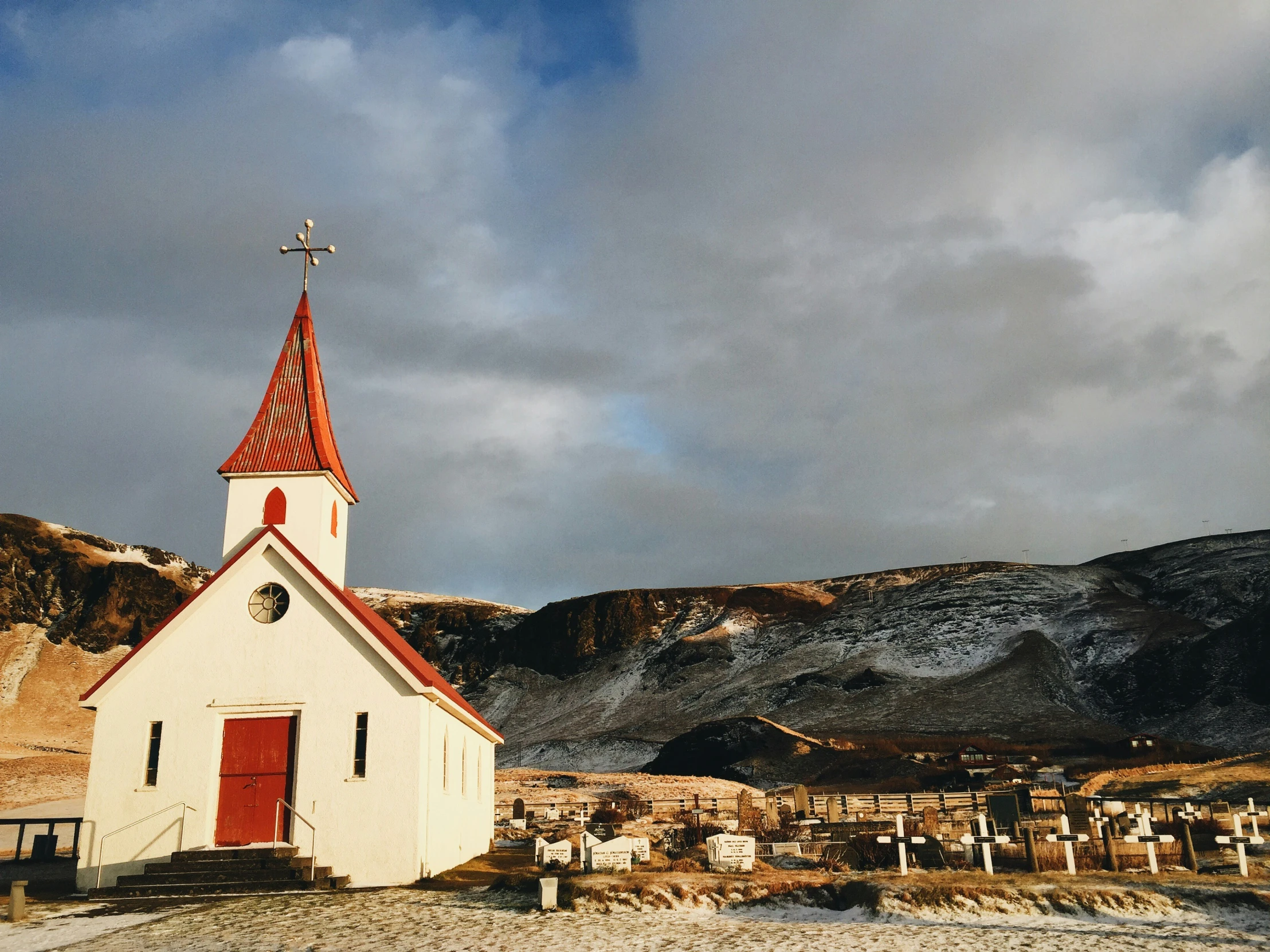 small white church with a cross on top in the mountains