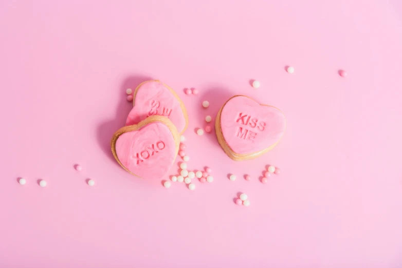 the pink cookies are heart shaped with the words kiss me