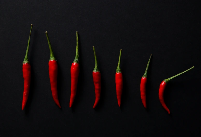 four chilis are shown with stems in a row