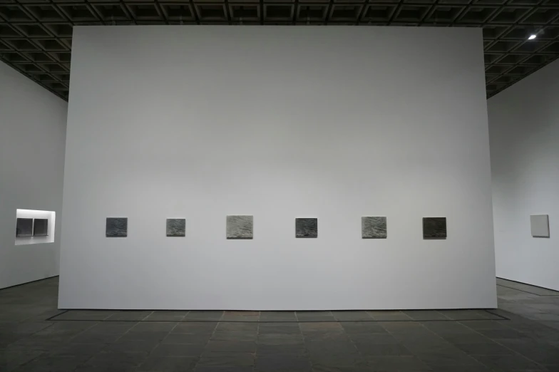 art works on a large white wall with four pographs on each of the walls