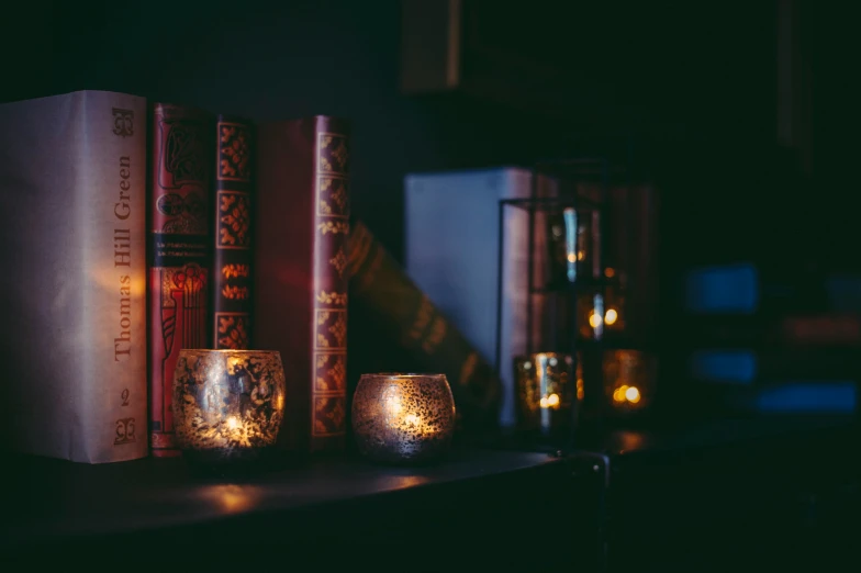 two books are sitting on a shelf with a candle