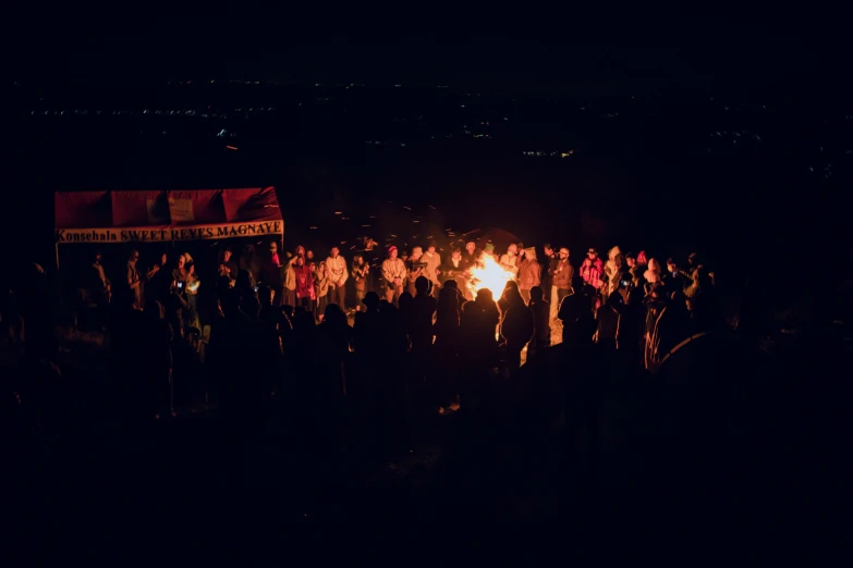 people are standing around a small fire pit