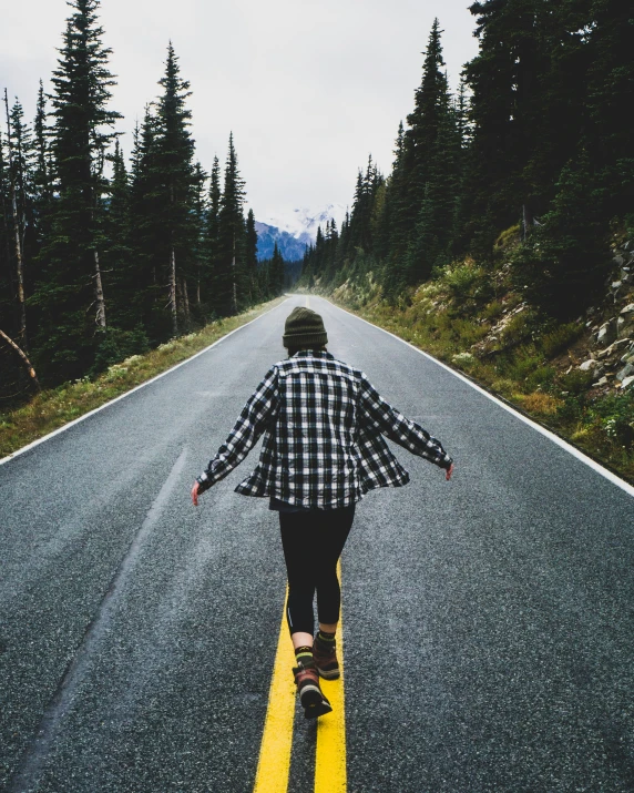 a person skate boarding on the middle of an asphalt road