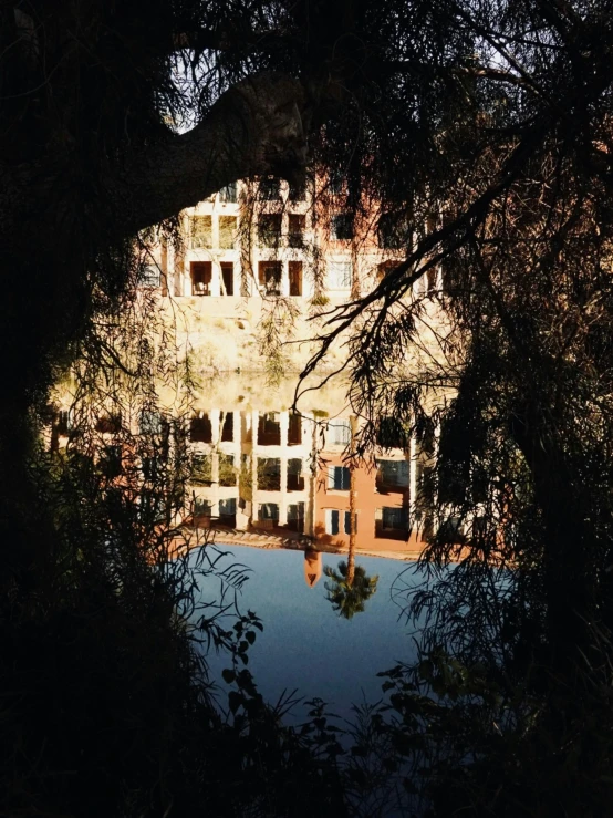 a large mansion is seen through a tree with light coming from the top