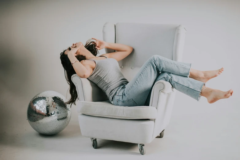 a woman sitting in a chair with her feet up on a mirror ball