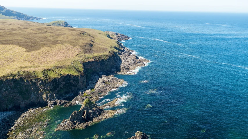 an aerial s of the cliffs and ocean with green grass