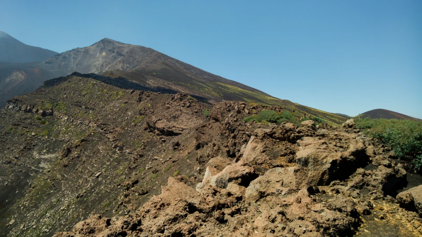 a small rocky mountain sitting below a blue sky