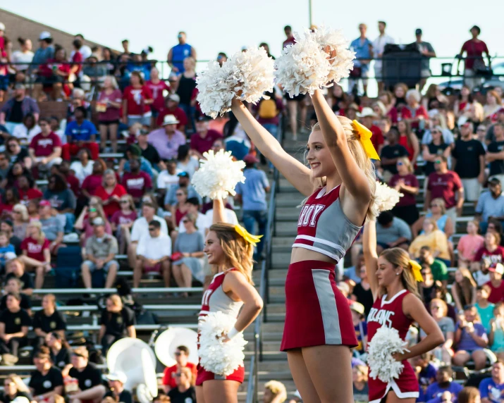 two girls with cheerleaders holding pom - poms perform