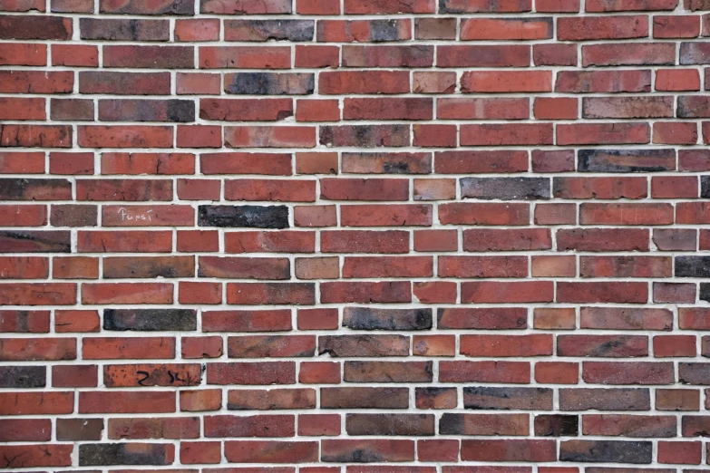 red brick building wall, containing a brick with small white letters