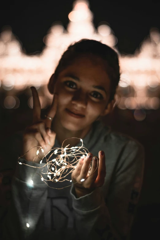 a boy with glasses has his finger up and a string of lights in front of him