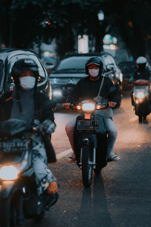 a man on a motorcycle wearing a face mask driving down the street