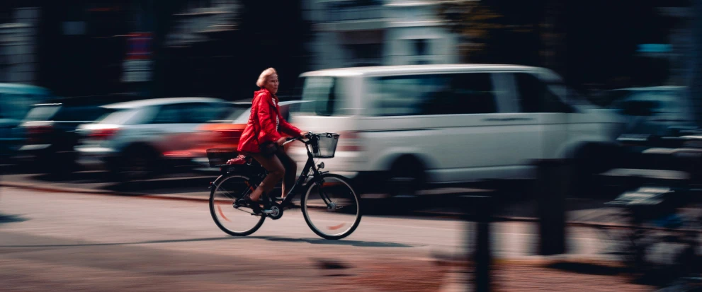 a person riding on a bicycle in a street with a van passing by