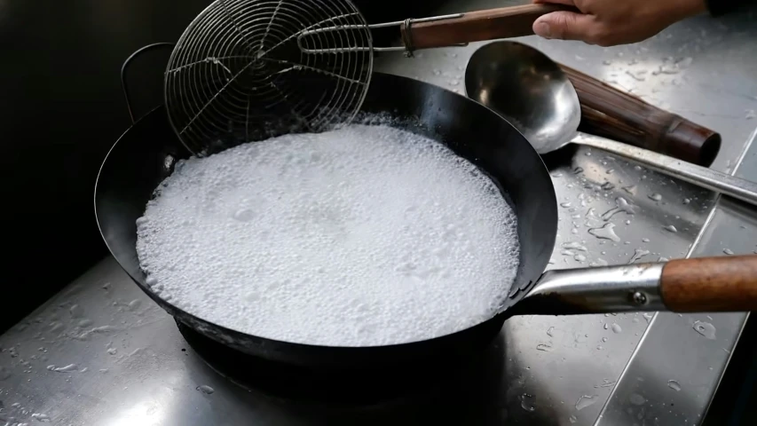 a pan with a mixture in it being stirred by two metal spoons