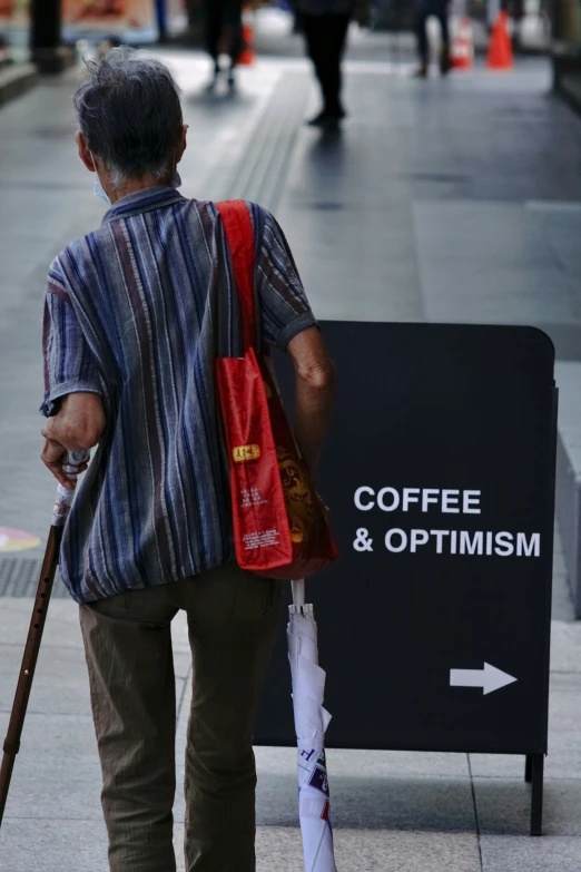 a man with an umbrella walks next to a coffee and opt trimm sign