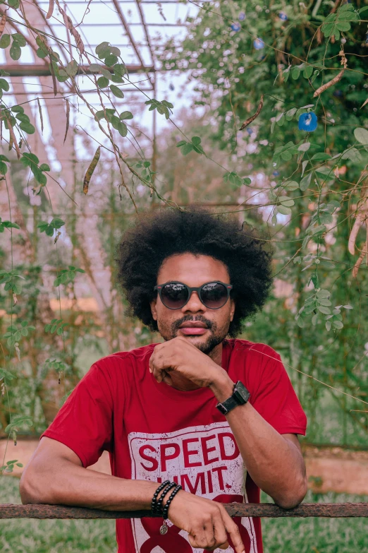 a person with a shirt and sunglasses posing near a fence