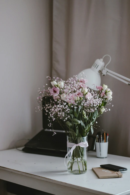 a vase filled with flowers next to a computer