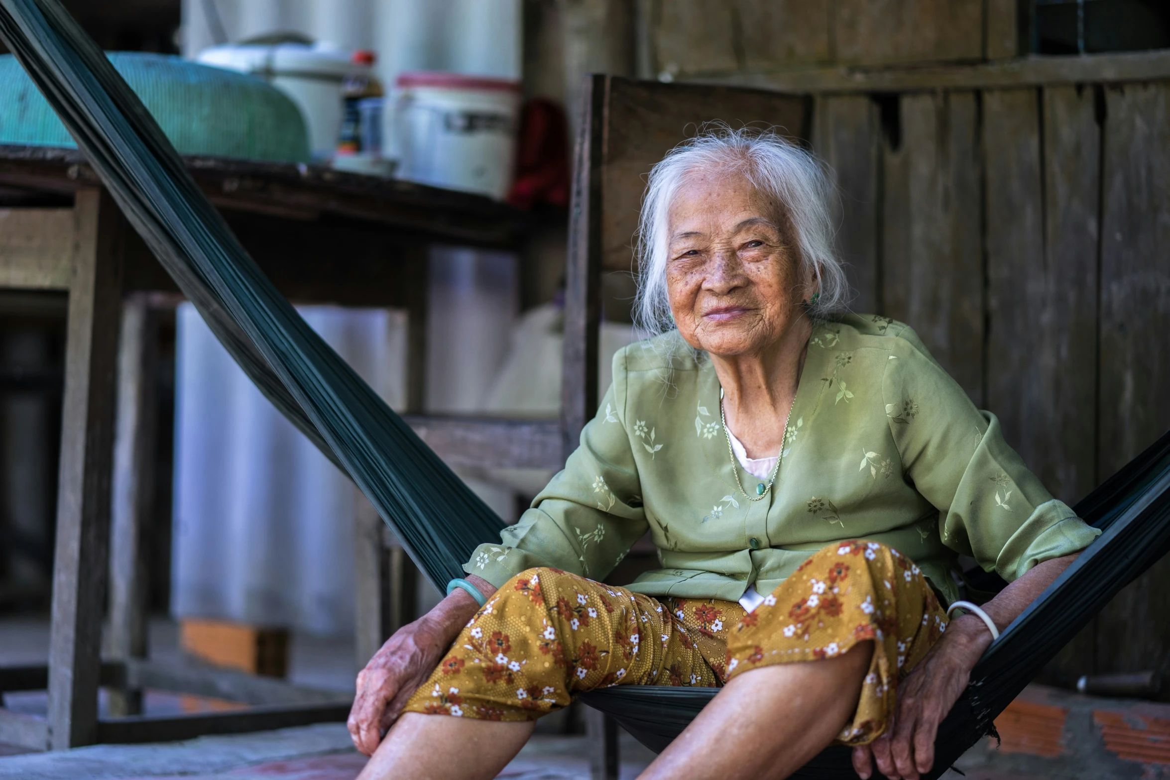 the older woman is sitting in a hammock