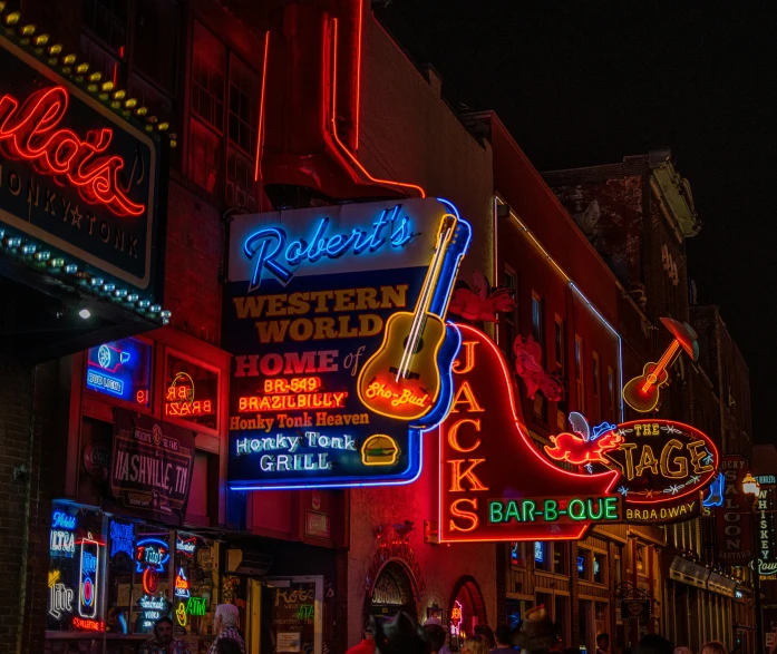 neon signs of musical band, guitar, and restaurant signs hang above an outdoor sidewalk