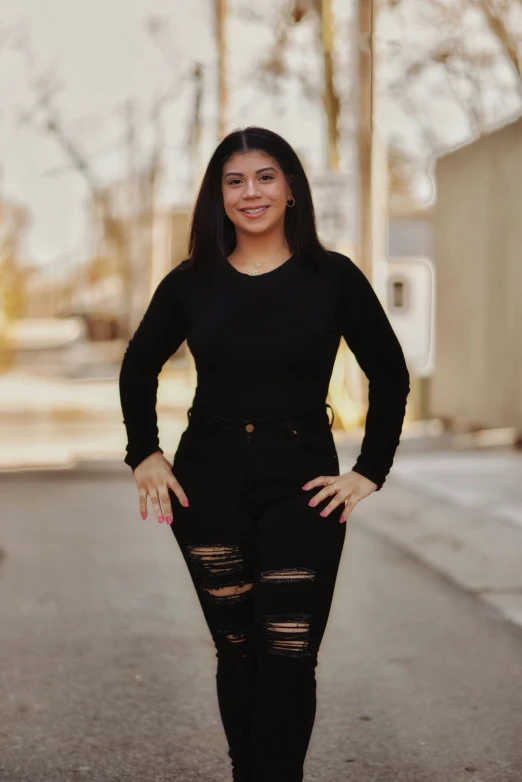 a woman posing in a black top with her arms on her hips