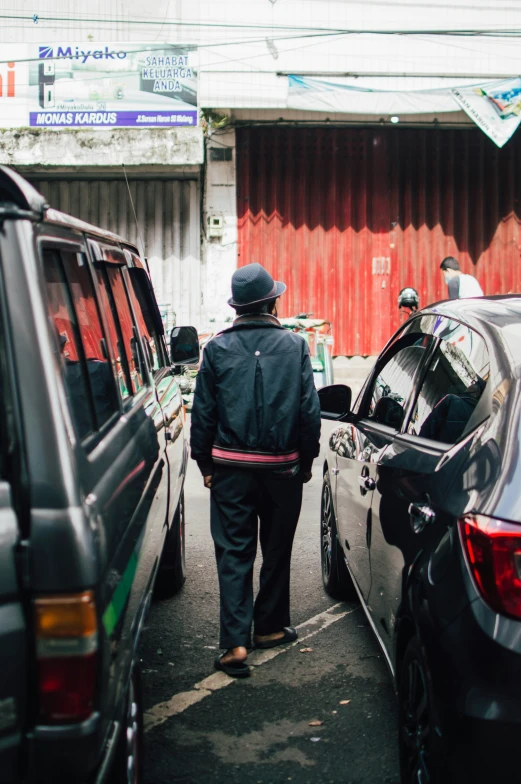 some men that are walking through some parked cars