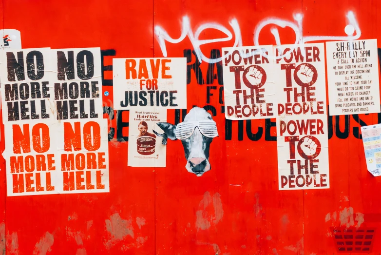 red wall with posters and slogans on it