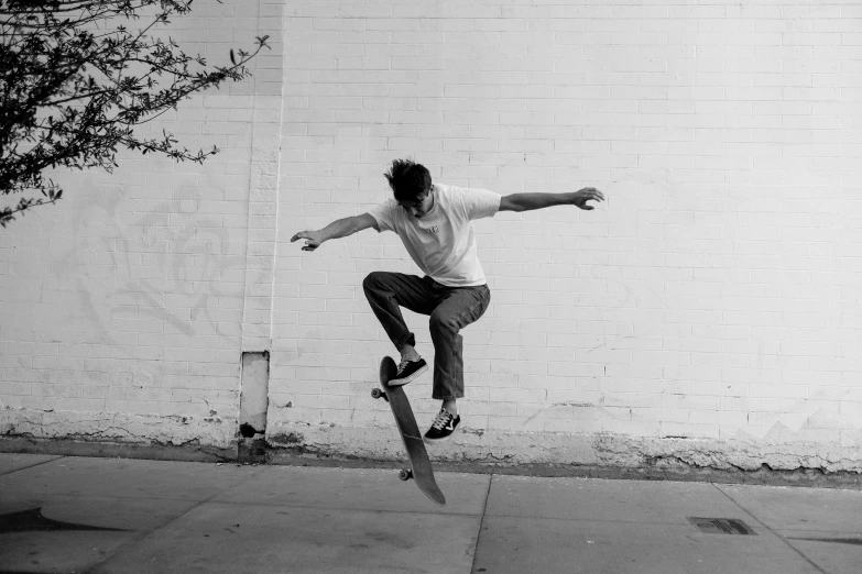 a young man performing a skateboard trick in front of a white wall