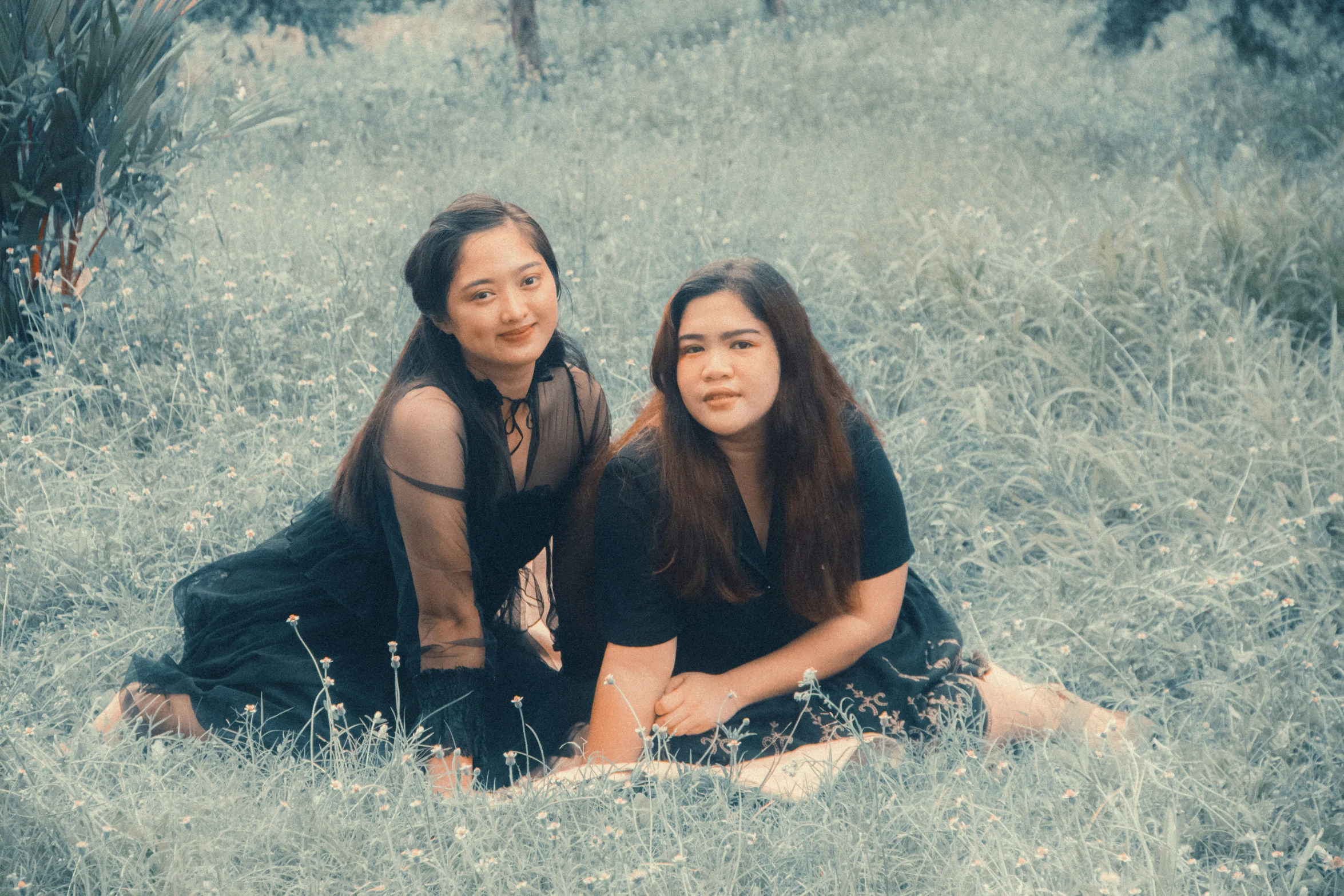 two women sitting on the ground posing for a picture