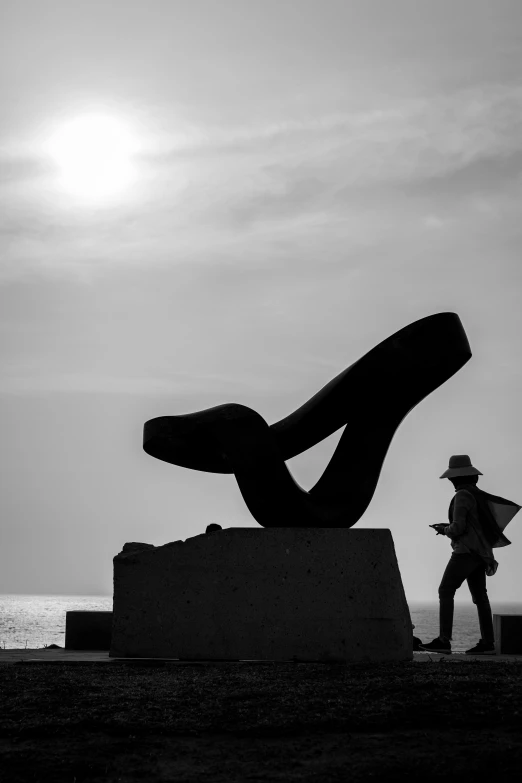 a sculpture sits on the ground with a woman in front of it