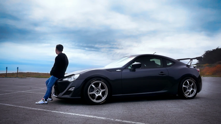 a man is standing next to a gray sports car