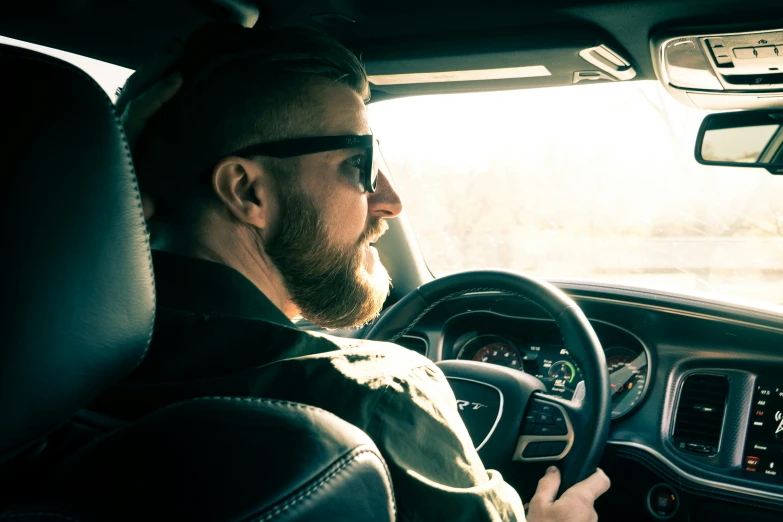 a man in sunglasses driving a car with headphones and sunglasses