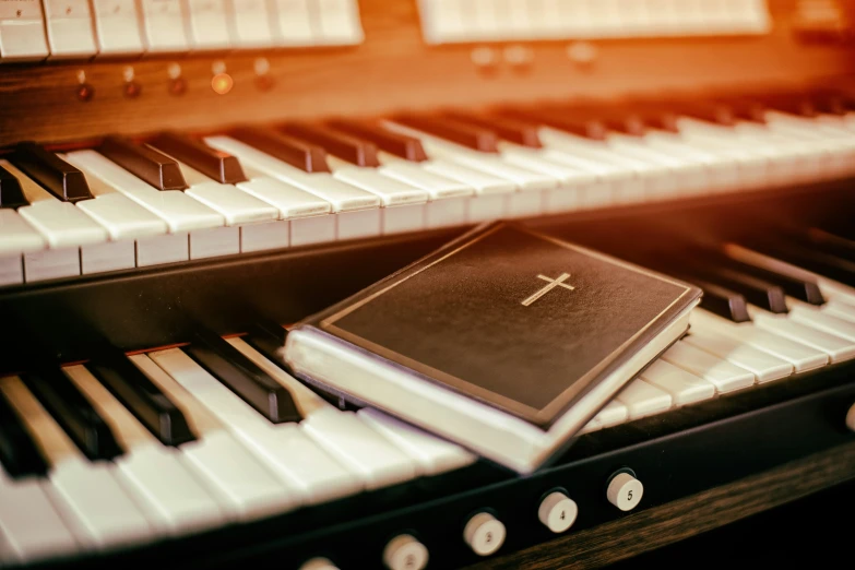 an old book sits on top of an organ keyboard