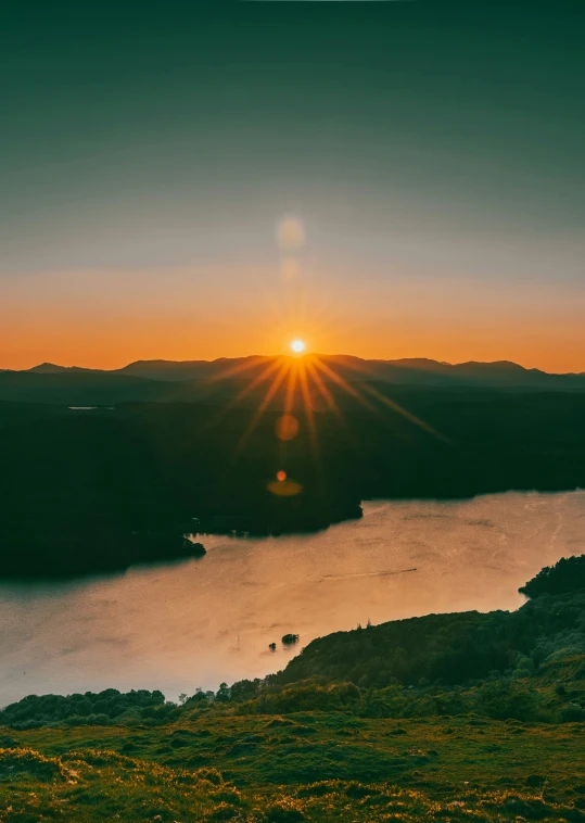 a sunset s over a body of water and hills